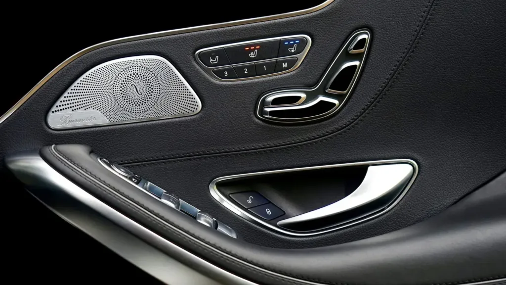 Inside of a car door panel with a speaker grille and window switches