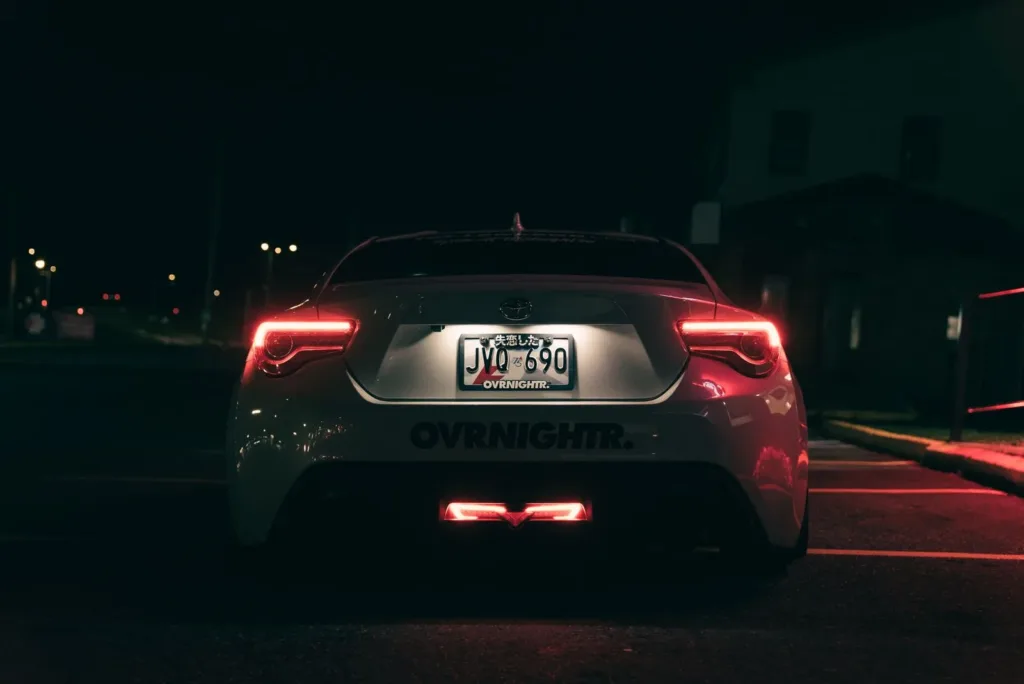 Rear of a car at night showing the tail lights and license plate