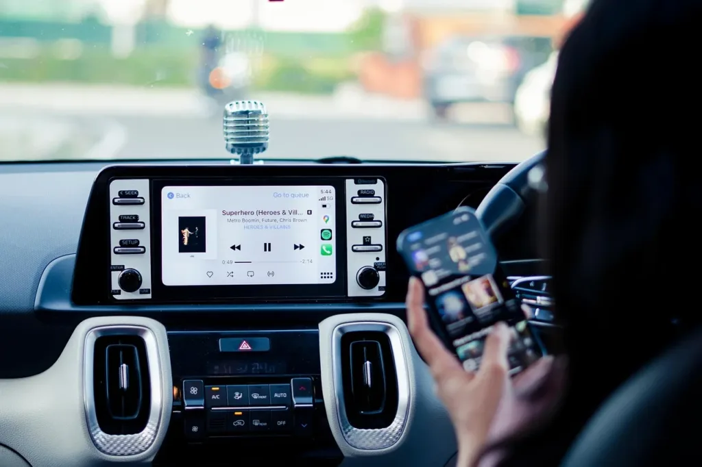 Driver holding a phone while music streams to a car touchscreen