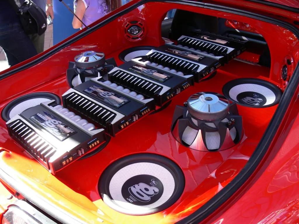 Red car trunk filled with amplifiers and subwoofers in a custom install