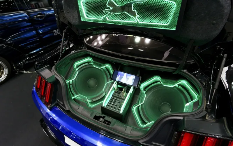 Car trunk fitted with an aftermarket audio system under green neon light