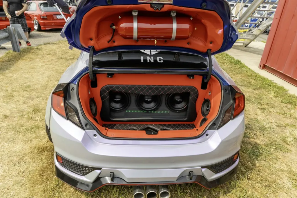 Custom car trunk build with subwoofers set into orange panels