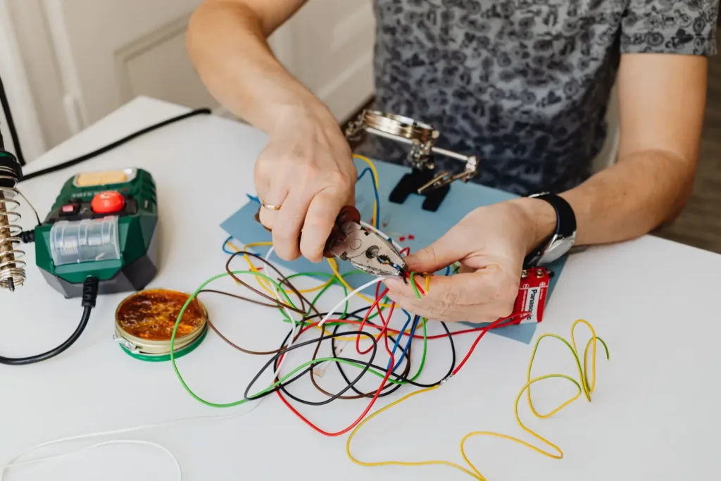 Hands trimming colored wires with pliers before connecting them