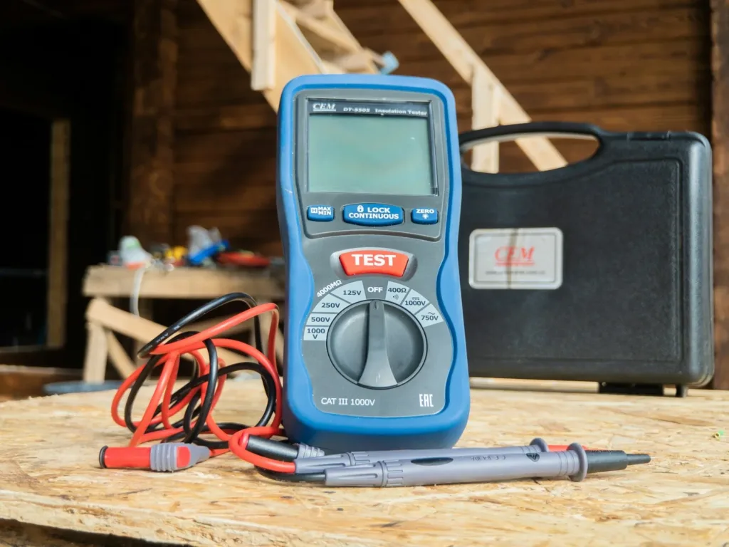 Blue digital multimeter with red and black test leads on a workbench