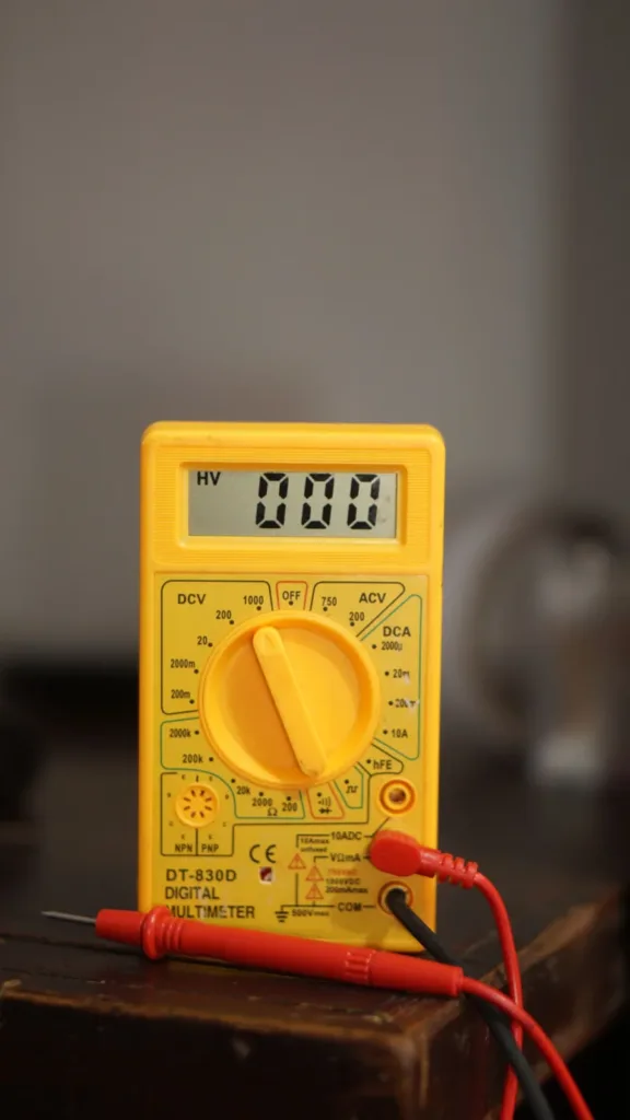 Yellow digital multimeter with test probes reading 0.00
