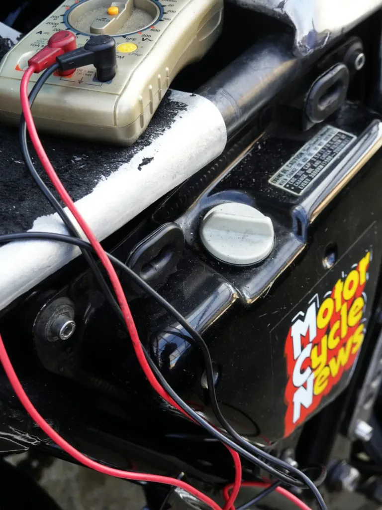 Multimeter leads clipped to a vehicle battery to read DC voltage