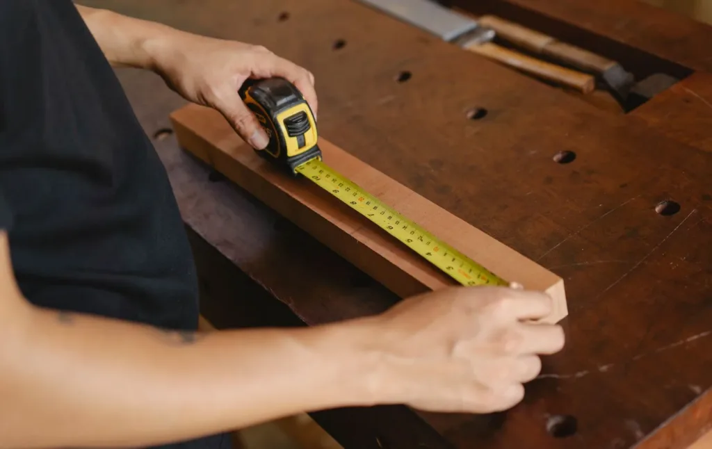 Tape measure stretched across a wooden plank on a workbench
