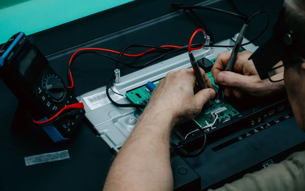 How to fix a blown car amplifier: a technician probing a circuit board with multimeter leads