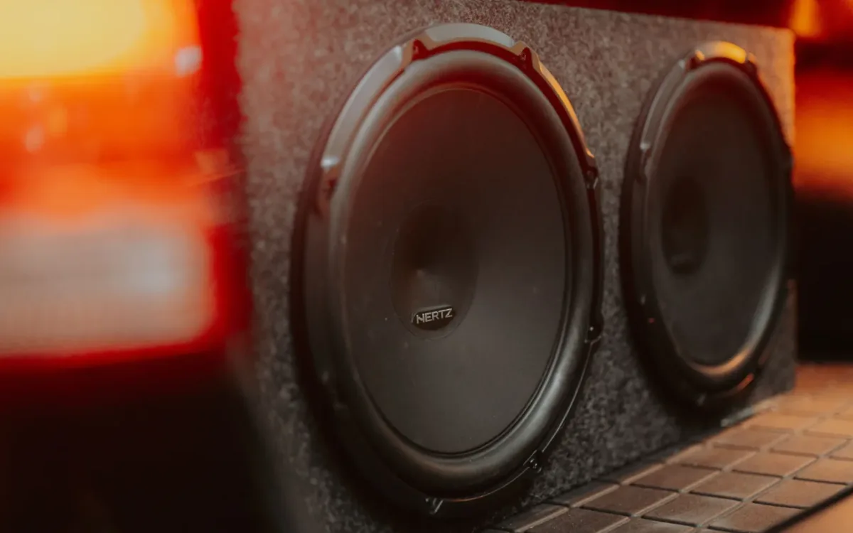 Two subwoofers in a carpeted box in a car trunk, the setup covered in this guide to the best amp for 2 12s