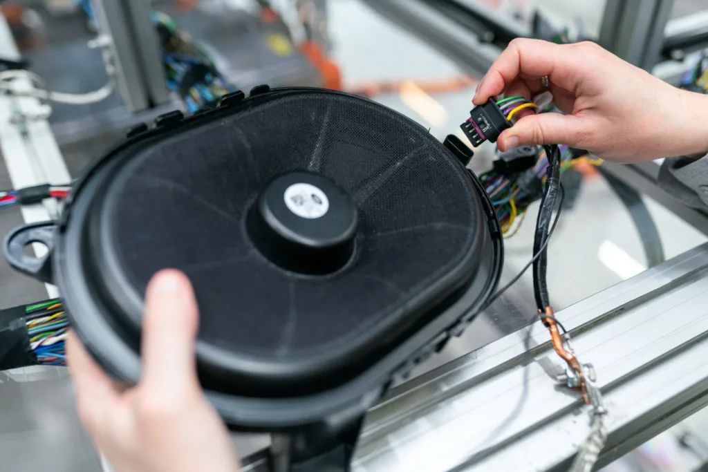 Hands holding a speaker and connecting its wiring plug