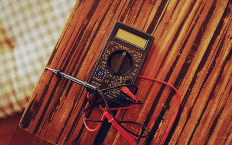 How to test a car subwoofer: digital multimeter with test leads on a wooden table